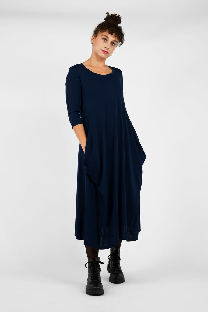 Feminin, schick, elegant aber zugleich lässig-casual.   Das Midi-Kleid aus fließendem, bi-elastischem Stoff sorgt für eine feminine Silhouette, hat aber zugleich lässige Eigenschaften: mit modisch gerafften Details unterhalb der Seitennahttaschen, weitem Rundhalsausschnitt und 3/4 Ärmeln. Hinten befindet sich eine mittige Naht, die Saumlinie vorne ist leicht abgerundet und verlängert. 