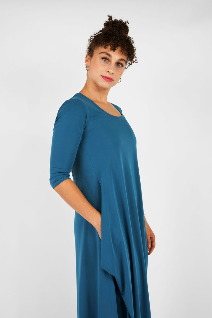 Feminin, schick, elegant aber zugleich lässig-casual.   Das Midi-Kleid aus fließendem, bi-elastischem Stoff sorgt für eine feminine Silhouette, hat aber zugleich lässige Eigenschaften: mit modisch gerafften Details unterhalb der Seitennahttaschen, weitem Rundhalsausschnitt und 3/4 Ärmeln. Hinten befindet sich eine mittige Naht, die Saumlinie vorne ist leicht abgerundet und verlängert.