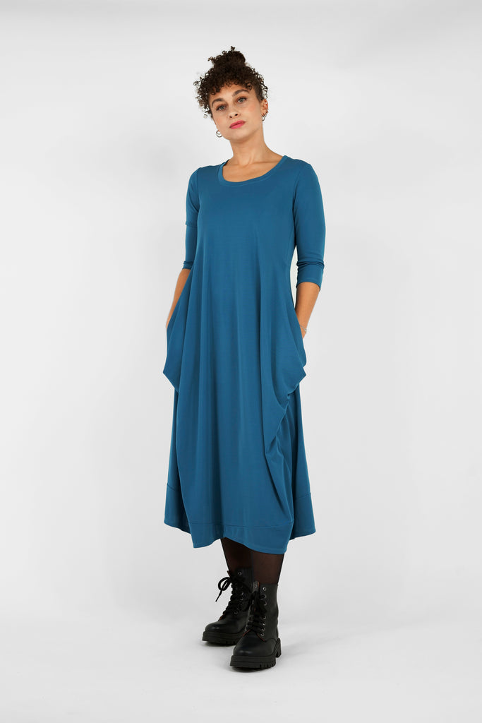 Feminin, schick, elegant aber zugleich lässig-casual.   Das Midi-Kleid aus fließendem, bi-elastischem Stoff sorgt für eine feminine Silhouette, hat aber zugleich lässige Eigenschaften: mit modisch gerafften Details unterhalb der Seitennahttaschen, weitem Rundhalsausschnitt und 3/4 Ärmeln. Hinten befindet sich eine mittige Naht, die Saumlinie vorne ist leicht abgerundet und verlängert.