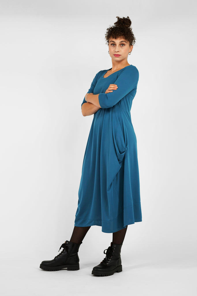 Feminin, schick, elegant aber zugleich lässig-casual.   Das Midi-Kleid aus fließendem, bi-elastischem Stoff sorgt für eine feminine Silhouette, hat aber zugleich lässige Eigenschaften: mit modisch gerafften Details unterhalb der Seitennahttaschen, weitem Rundhalsausschnitt und 3/4 Ärmeln. Hinten befindet sich eine mittige Naht, die Saumlinie vorne ist leicht abgerundet und verlängert.